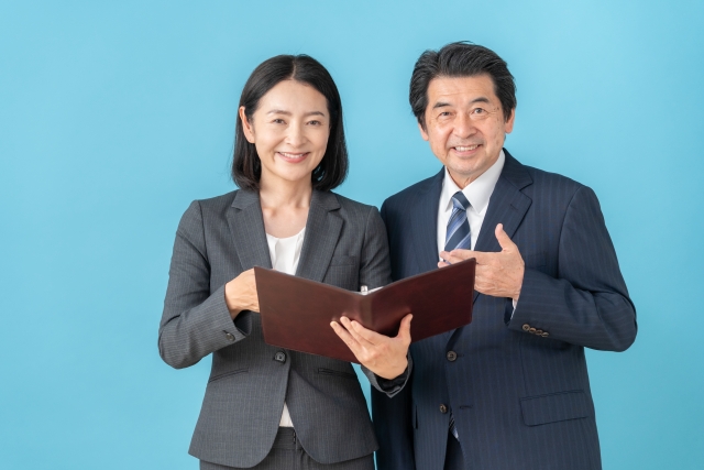 スーツの男女がノートを開き微笑んでいる