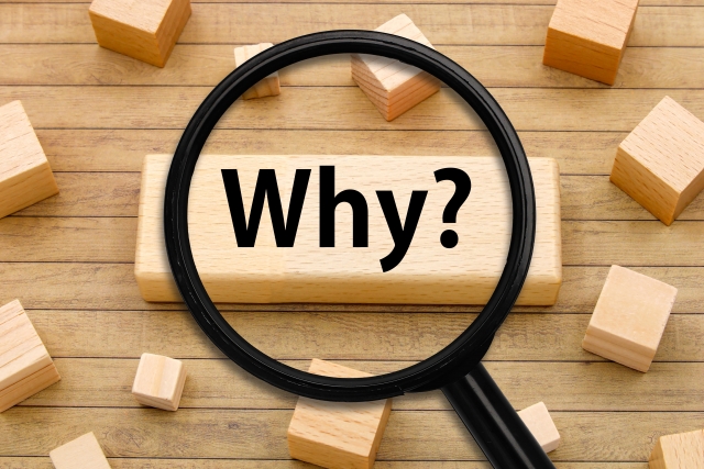虫眼鏡が「Why？」と書かれた木製ブロックにかざされている