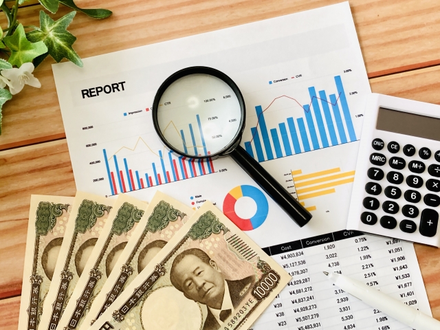 現金と電卓と虫眼鏡がテーブルに置かれている