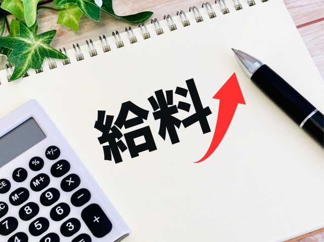 給料と書かれた紙の上に電卓とボールペンが置かれている