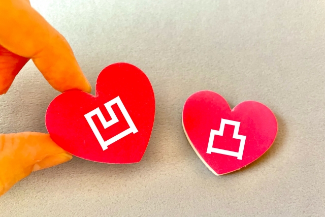 凹凸の文字が書かれたハートのタグをつまむ指